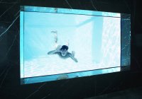 Homem olhando através da janela subaquática na piscina — Fotografia de Stock
