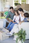 Family looking at picture frame on sofa among cardboard boxes — Stock Photo