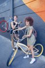 Portrait smiling friends with bicycles next to urban wall — Stock Photo