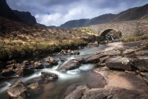 Поток течет под удаленным акведуком, Шотландия — стоковое фото