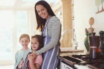 Портрет усміхненої матері і дочок на кухні — стокове фото