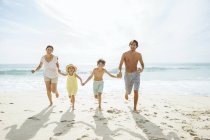 Сім'я біжить разом на пляжі — стокове фото