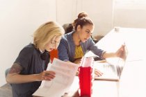 Kreative junge Geschäftsfrauen mit Laptop und Papierkram im Büro — Stockfoto