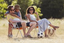 Усміхнена сім'я відпочиває на сонячному полі — стокове фото
