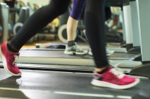 Женские ноги бегают по беговой дорожке в спортзале — стоковое фото