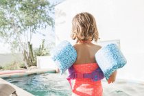 Menina criança em asas de água na borda da piscina — Fotografia de Stock