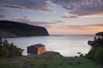 Boathouse overlooking calm bay at sunrise — Stock Photo