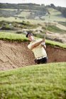 Uomo che oscilla dalla trappola di sabbia sul campo da golf — Foto stock