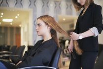 Парикмахер готовится сократить клиентов длинные волосы в салоне — стоковое фото