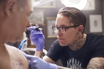 Focused tattoo artist preparing tattoo gun at studio — Stock Photo