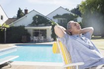 Hombre relajante en silla de salón en la piscina - foto de stock
