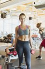 Portrait smiling woman holding dumbbells in gym — Stock Photo