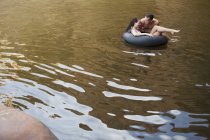Пара играет во внутренней трубке в озере — стоковое фото