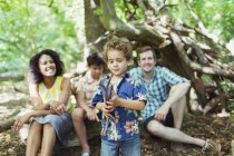 Famille regarder garçon jouer avec des bâtons dans les bois — Photo de stock