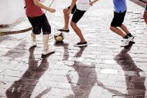 Niños jugando con pelota de fútbol en el callejón - foto de stock