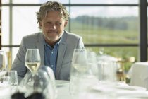 Portrait confident man with white wine at sunny restaurant table — Stock Photo