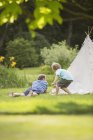Father and son laying outside teepee — Stock Photo