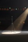 Microphone in spotlight on empty theater stage — Stock Photo
