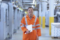 Portrait confident worker in reflective clothing with clipboard in factory — Stock Photo