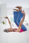 Portrait playful mature woman falling onto bed — Stock Photo