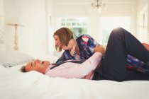 Well-dressed mature couple laughing on bed — Stock Photo