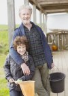 Portrait grandfather and grandson with bucket and net on porch — Stock Photo