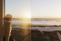 Безтурботна жінка дивиться захід сонця над океаном — стокове фото