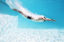 Вид человека, ныряющего в бассейн сбоку — стоковое фото