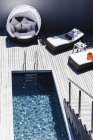 Chaises longues sur terrasse en bois près de la piscine — Photo de stock