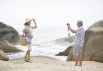 Homem mais velho tirando fotos de namorada na praia — Fotografia de Stock