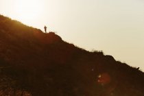 Silhouette of runner ascending hillside at sunset — Stock Photo
