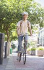 Молода жінка з шоломом їде на велосипеді в міському парку — стокове фото