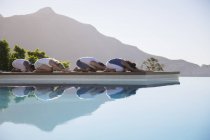 Jovens pessoas atraentes praticando ioga na beira da piscina — Fotografia de Stock