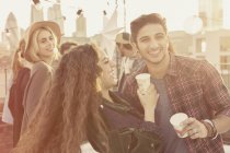 Young adult friends drinking and laughing at rooftop party — Stock Photo