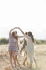 Женщины Бохо танцуют в кругу на солнечном сельском поле — стоковое фото