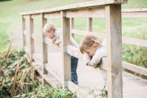 Toddler children leaning on footbridge railing in park — Stock Photo