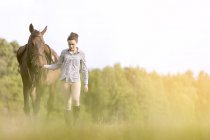 Mulher andando cavalo no campo rural — Fotografia de Stock