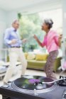 Playful nature couple dancing in living room behind record player — Stock Photo