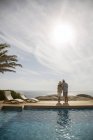 Casal mais velho abraçando por piscina — Fotografia de Stock