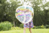 Отец и дочь играют с большими пузырьками на заднем дворе — стоковое фото