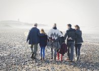 Familia multigeneracional caminando en fila en la playa - foto de stock