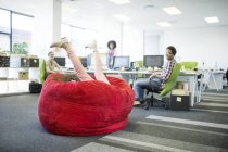 Businesswoman playing in beanbag chair in office — Stock Photo