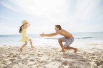 Father and daughter playing on beach — Stock Photo
