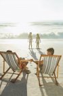 Genitori che guardano le figlie sulla spiaggia al tramonto — Foto stock