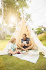 Father and son using digital tablet in teepee in backyard — Stock Photo