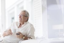 Старший чоловік слухає навушники на патіо — стокове фото
