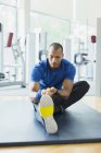 Mann benutzt Widerstandsband, um Bein im Fitnessstudio zu strecken — Stockfoto