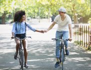 Пара тримає руки їзда на велосипедах у міському парку — стокове фото