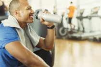 Lächelnder Mann trinkt Wasser im Fitnessstudio — Stockfoto