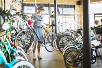 Mulher selecionando bicicleta de rack na loja de bicicletas — Fotografia de Stock